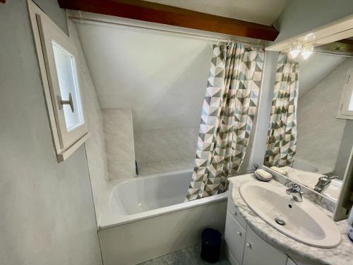 une salle de bain avec un lavabo et une baignoire dans l'établissement Maison paisible, piscine, plages à 500m, à Clohars-Carnoët