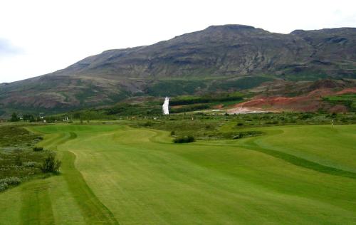 a golf course with a mountain in the background at Geysir Cabins - Golden Circle Cabin only 800m from Geysir in Selfoss