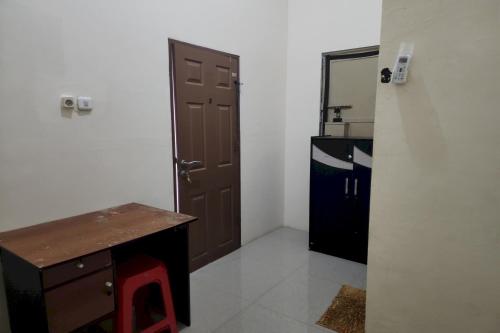 a room with a door and a desk and a kitchen at OYO 93865 Dv Homestay Syariah Kupang in Surabaya