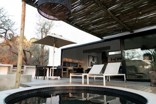 un patio con piscina, mesa y sillas en Ivory House, en Marloth Park