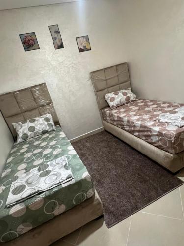 2 Betten in einem Zimmer mit Bildern an der Wand in der Unterkunft Selouan in Selouane