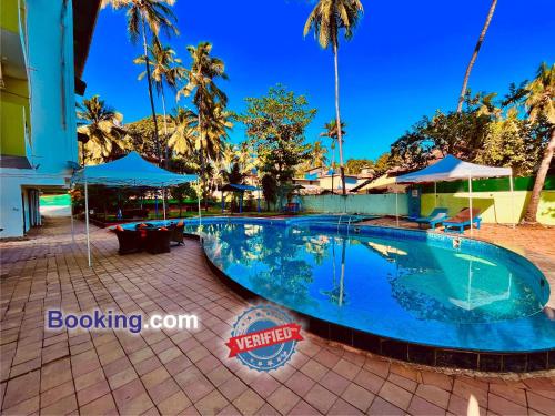 a swimming pool at a resort with palm trees at Hotel The Golden Shivam Resort - Big Swimming Pool Resort In Goa in Goa