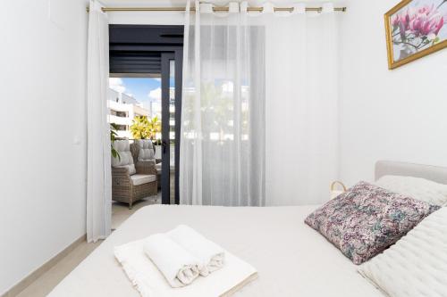 a white bedroom with a bed and a balcony at Flamenco Village Elvira in Orihuela