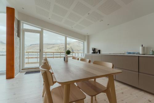 a dining room with a wooden table and chairs at Seaside Nest - Charming Waterfront Retreat in Vestmanna