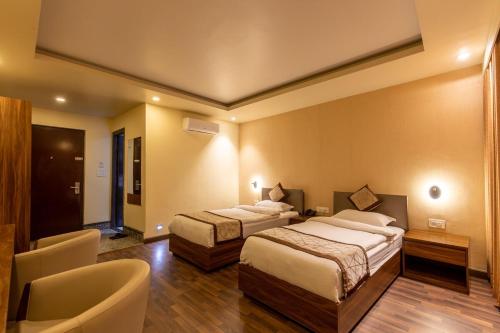 a hotel room with two beds and a chair at Gorakha Hotel Pvt Ltd in Itahari