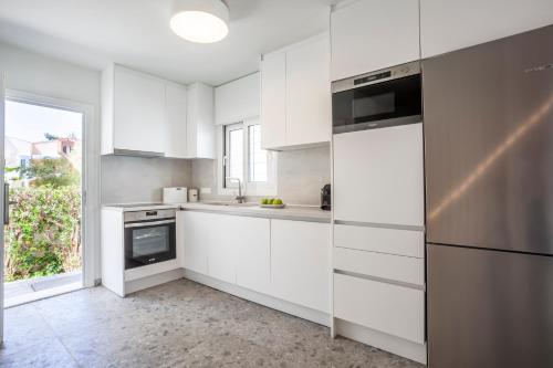 a kitchen with white cabinets and a stainless steel refrigerator at Serenity Seafront garden villa in Pefkohori