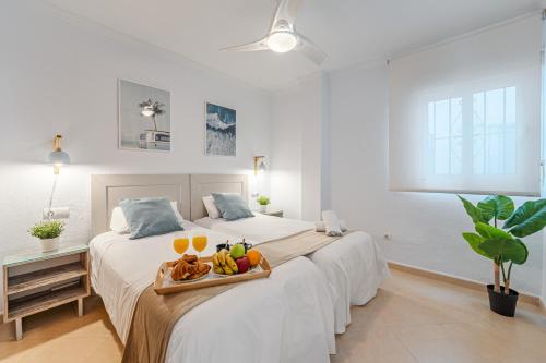 - une chambre blanche avec 2 lits et un plateau de fruits dans l'établissement CARIHUELA - Beach & Sun, à Torremolinos