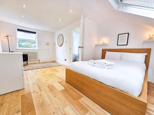um quarto com uma grande cama branca e pisos em madeira em Fresh & Modern House with Games Room & Garden em Londres