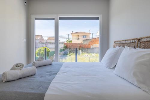 1 dormitorio con 1 cama blanca grande y ventana grande en Poolside oasis by Caparica beach, en Charneca