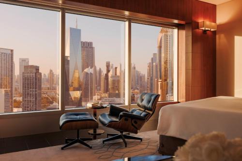 a bedroom with a bed and two chairs and a large window at Jumeirah Emirates Towers Dubai in Dubai