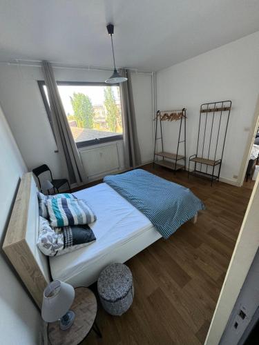 een slaapkamer met een bed en een raam met 2 stoelen bij Rijsel Vlamse in Lille