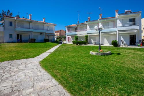 a large white house with a green lawn at Serenity Seafront garden villa in Pefkohori