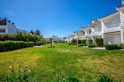 a row of white houses on a green lawn at Serenity Seafront garden villa in Pefkohori