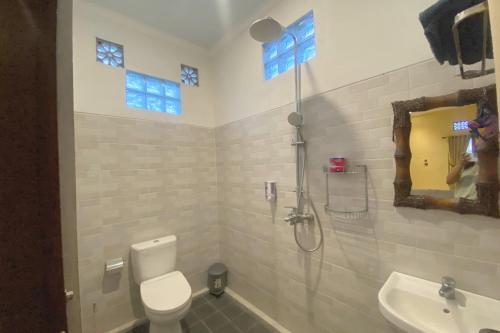 a bathroom with a shower and a toilet and a sink at Capital O 93844 Arta Adi Homestay in Bangli