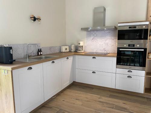 une cuisine avec des armoires blanches et un évier dans l'établissement Gîte paisible au style rétro, à Réty