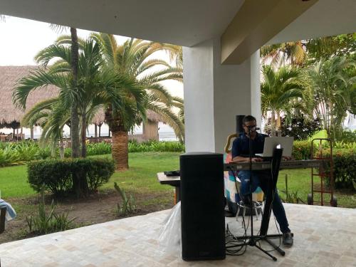 a man sitting at a table with a laptop at Hotel y villas palma Real . in La Ceiba