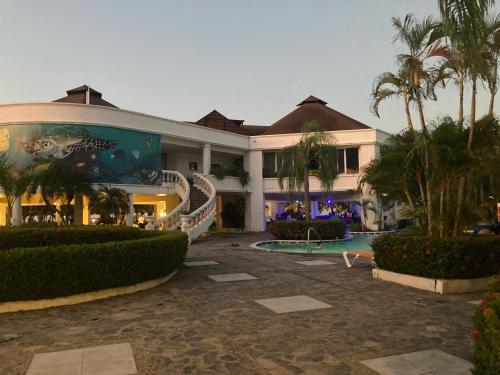 a large building with a swimming pool and palm trees at Hotel y villas palma Real . in La Ceiba