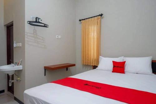 a bedroom with a white bed with a red pillow and a sink at Ilfa Guest House syari'ah in Jatiwangi
