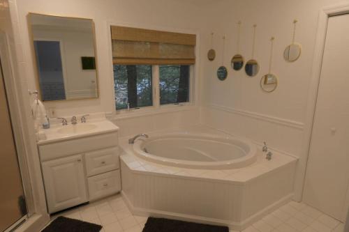 a white bathroom with a tub and a sink at Catskills Lakefront Escape with Hot Tub in Monticello