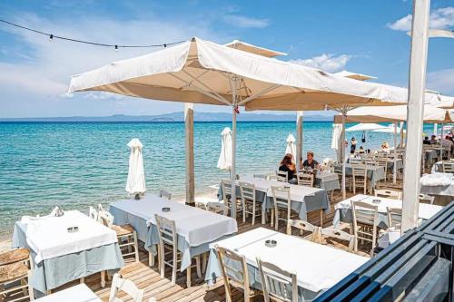 a restaurant on the beach with white tables and umbrellas at Serenity Seafront garden villa in Pefkohori