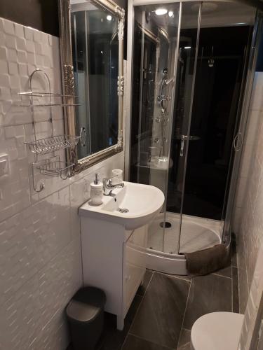 ein weißes Bad mit einem Waschbecken und einer Dusche in der Unterkunft Corner Apartman 5 in Siófok