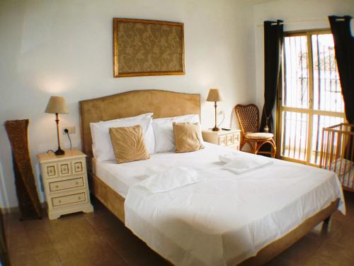 a bedroom with a large white bed and a window at Casa Ladera in Las Lagunas Mijas