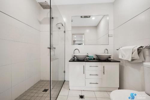 a white bathroom with two sinks and a shower at Batemans Bay Apartment in Batemans Bay