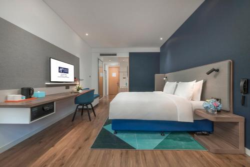 a bedroom with a large bed with a desk and a computer at Holiday Inn Express Qingdao Chengyang Central by IHG in Qingdao