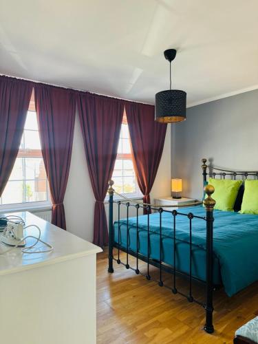 3 bed West Norwood Apartment في West Dulwich: غرفة نوم مع سرير وملاءات زرقاء وستائر أرجوانية