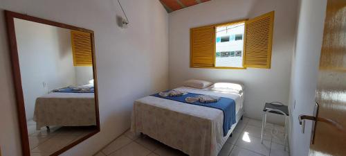 Una pequeña habitación con dos camas y un espejo. en Casa em Porto de Galinhas - PRIVÊ DAS ONDAS, en Porto de Galinhas