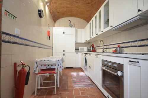 a kitchen with white cabinets and a table in it at Casa Fernanda in Fuzeta