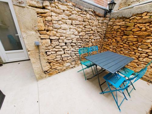 einen Tisch und Stühle vor einer Steinmauer in der Unterkunft Appartement climatisé avec extérieur à Sarlat in Sarlat-la-Canéda