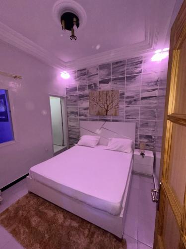 sypialnia z białym łóżkiem i ścianą w obiekcie Welltima Teranga w mieście Dakar