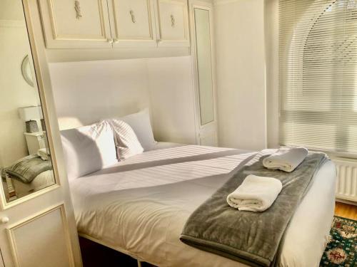 a white bedroom with a bed with two towels on it at Marina Waves Apartment- Brighton, free parking, patio, ground-floor holiday home, one bedroom, sleeps 3 in Brighton & Hove