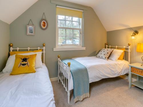 2 camas individuales en una habitación con ventana en River Cottage, en Enochdhu