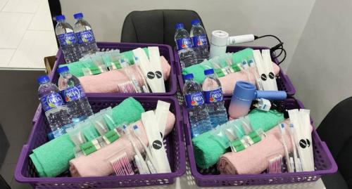 two purple containers filled with bottles of water and towels at ankang in Alor Setar