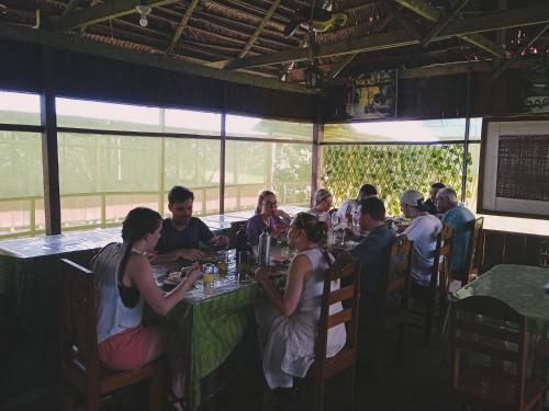 Bromelia Flower Lodge Iquitos في إكيتوس: مجموعة من الناس يجلسون على طاولة في مطعم
