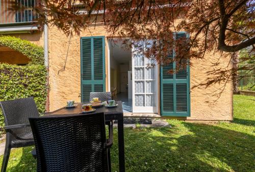 a table and chairs in front of a house with green shutters at Emma's House in Lierna