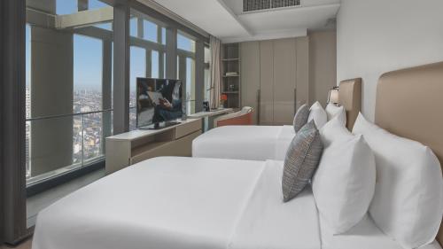 two white beds in a room with a window at Oakwood Makati Avenue in Manila