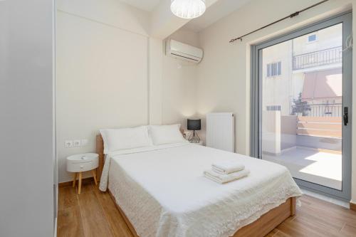 a white bedroom with a bed and a large window at Luxury penthouse near Acropolis in Athens