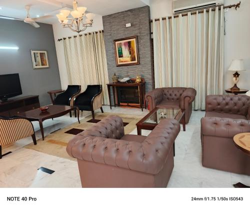a living room with leather couches and a tv at Palladium Executive in Islamabad