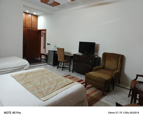 a hotel room with a bed and a chair and a desk at Palladium Executive in Islamabad