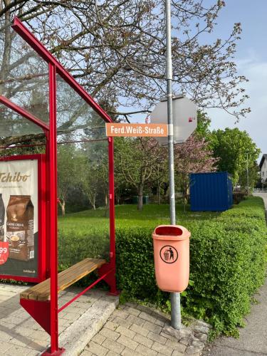 a red phone booth with a trash can next to a street sign at Small attic apartment close to Lake and Mountains Fussach in Fußach