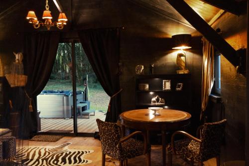 una sala da pranzo con tavolo e sedie in legno di L ost in Sensations -Hébergements Insolites et Suites de luxe Spa Sauna Piscine Forêt a Marcenas