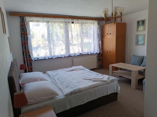 sypialnia z łóżkiem, oknem i stołem w obiekcie Pension U Stašáků w mieście Jetřichovice
