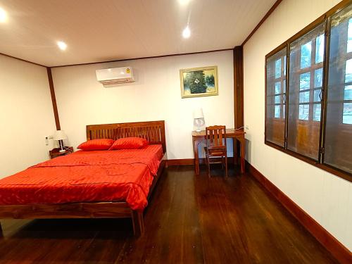 a bedroom with a bed and a table and a window at Isaan Perazim Park in Roi Et