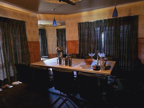uma sala de jantar com uma mesa de madeira e cadeiras em The Citadel em Srinagar