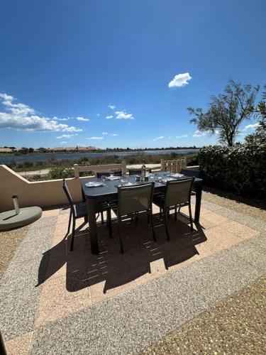 Une table à manger et des chaises noires sont disponibles sur la terrasse. dans l'établissement Le lagon vue dégagée, à Gruissan