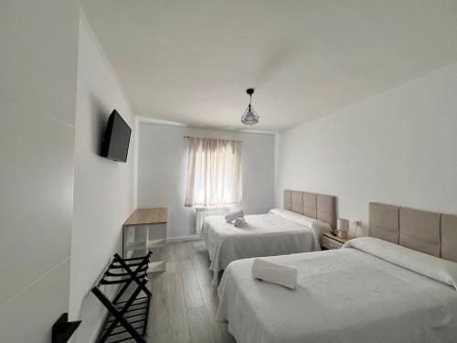 een hotelkamer met 2 bedden en een bank bij El descanso de la Covatilla in Béjar