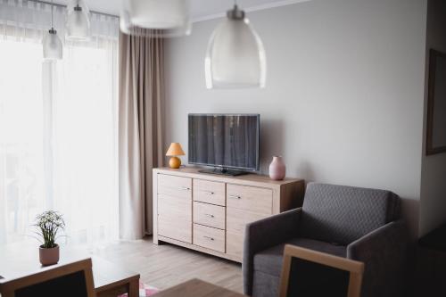a living room with a tv on a dresser at Rezydencja Park Mielno in Mielno